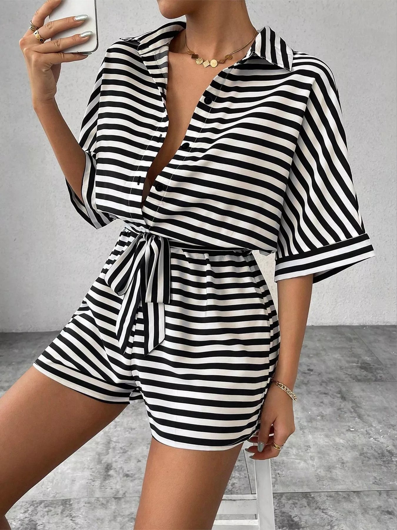 Striped button-up belted romper by Trendsi featuring a stylish design, lightweight fabric, and a waist belt for a chic summer look.