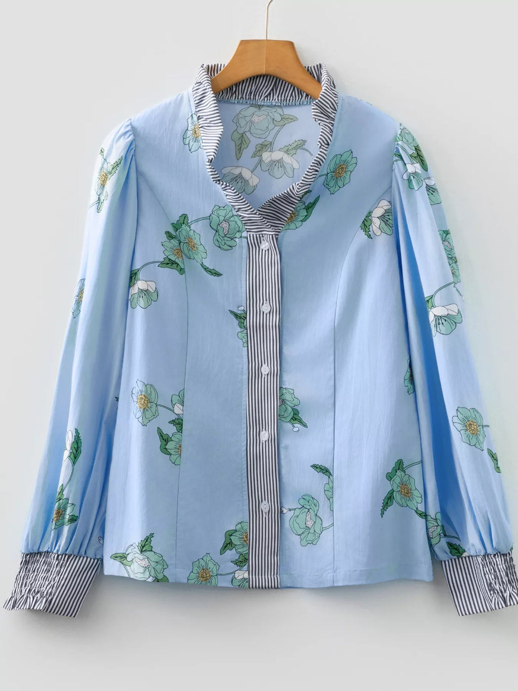 Floral print ruffled V-neck blouse with striped trim, trendy Tops by Trendsi, showcasing the detailed floral design and ruffled neckline.