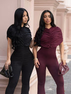 Black ruched flare leg jumpsuit from Trendsi with a fitted bodice and wide flare pants, perfect for stylish casual wear.
