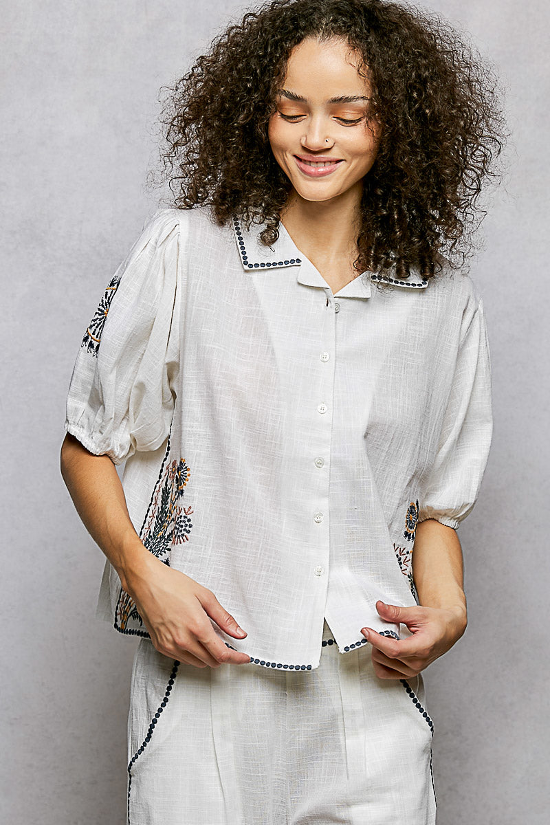Women's floral embroidered cotton button-down short sleeve shirt by Plush Fashion Hub, featuring colorful floral embroidery on crisp white fabric.