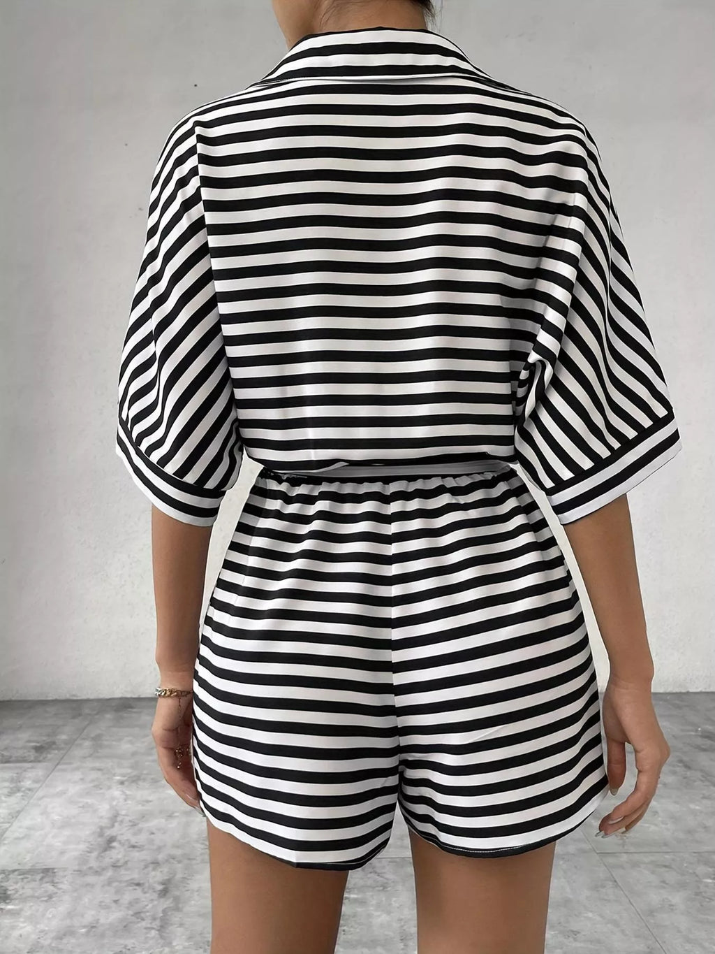 Striped button-up belted romper by Trendsi featuring long sleeves, a waist belt, and a casual, stylish design.