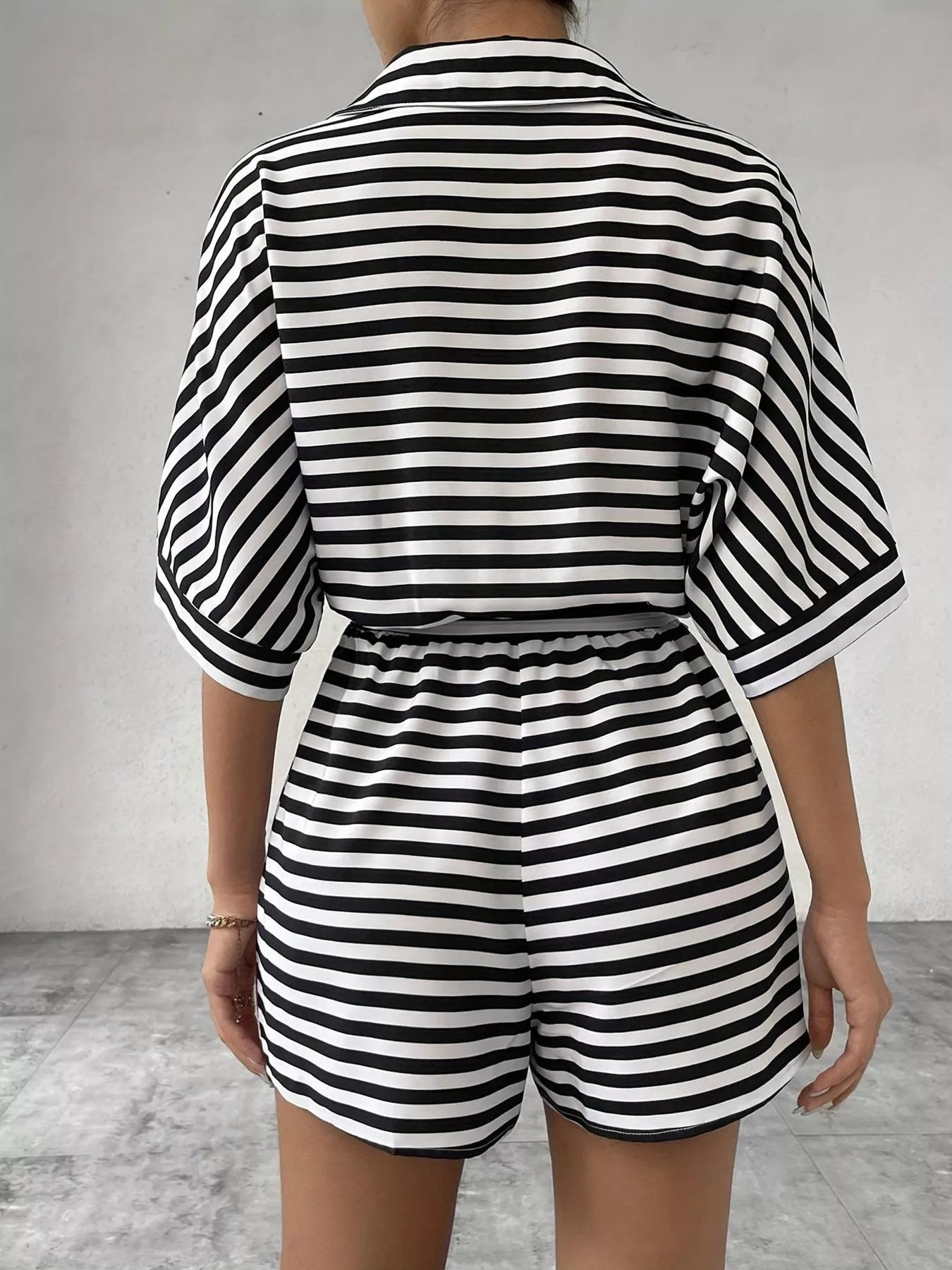 Striped button-up belted romper by Trendsi featuring long sleeves, a waist belt, and a casual, stylish design.