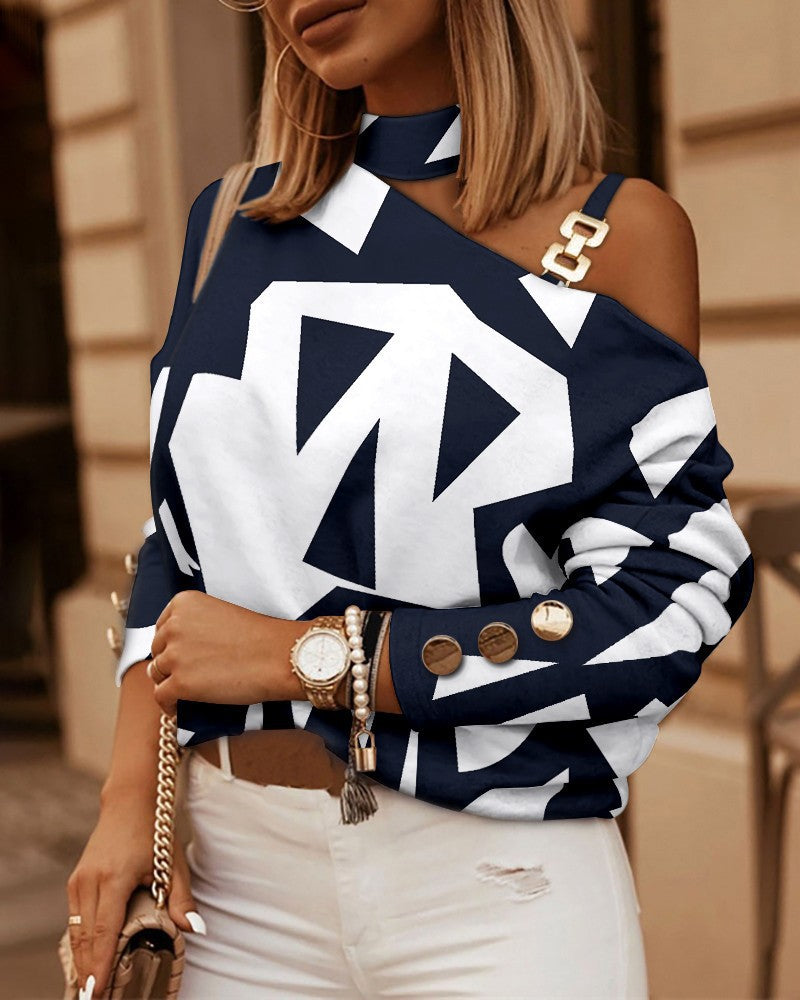 Navy and white geometric print cold-shoulder top with a choker neck, gold chain link strap, and buttoned sleeves.