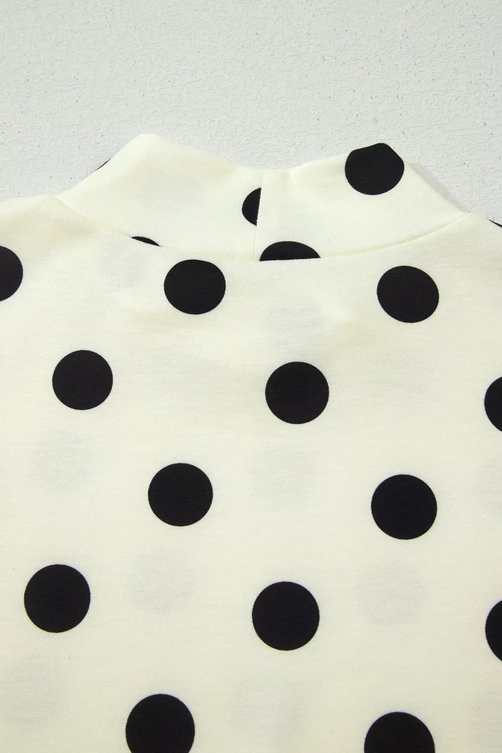 Polka dot print high neck dolman top by Trendsi, featuring a relaxed fit and stylish design, shown in a close-up image.