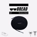 Coiled 18-inch "Shadow Black" BREAD branded shoelace with aglets, featuring a white logo on a black background.