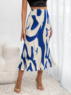 A high-waisted, pleated midi skirt featuring a bold blue and cream abstract graphic pattern.