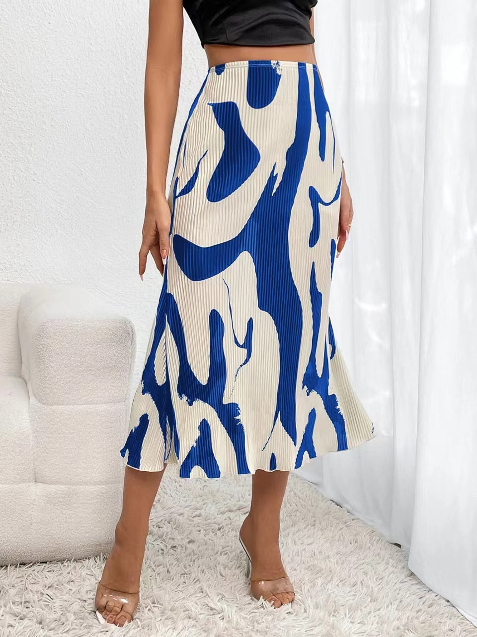 A high-waisted, pleated midi skirt featuring a bold blue and cream abstract graphic pattern.