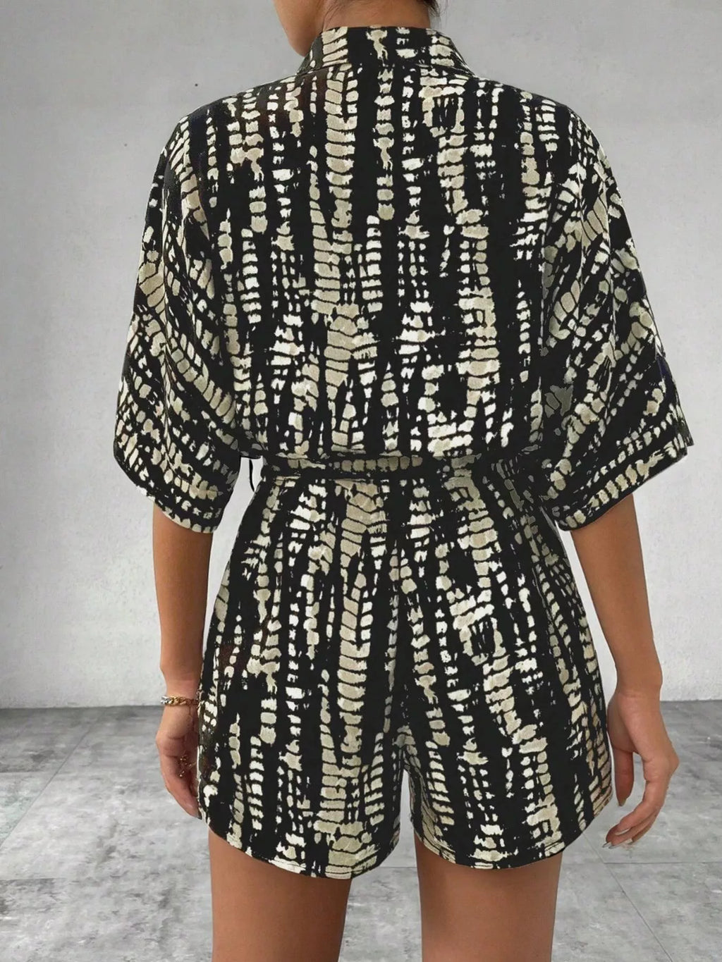 Striped button-up belted romper from Trendsi featuring a stylish design and waist tie, perfect for casual and summer wear.