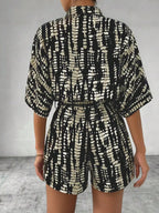 Striped button-up belted romper from Trendsi featuring a stylish design and waist tie, perfect for casual and summer wear.