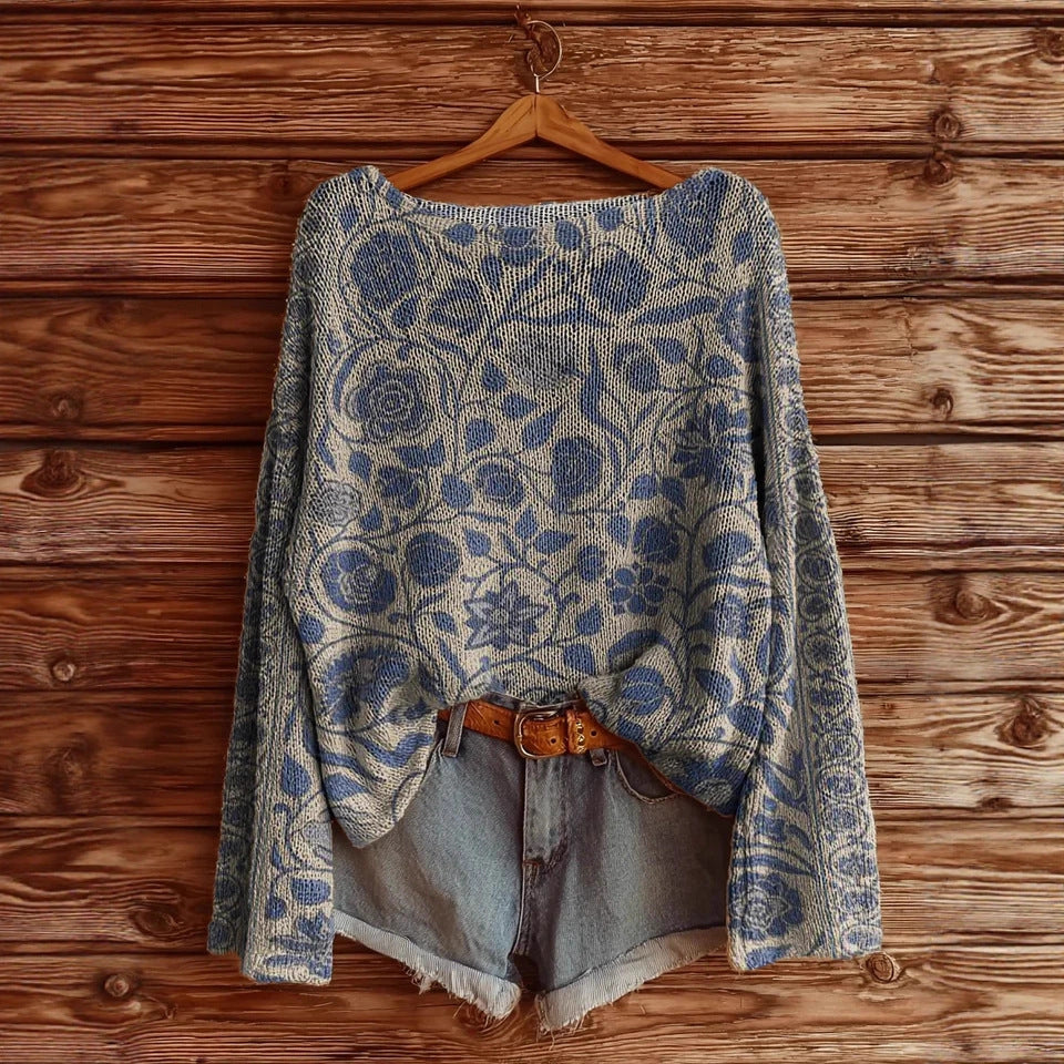 Blue and cream floral knit sweater paired with denim shorts and a brown leather belt against a wooden background.