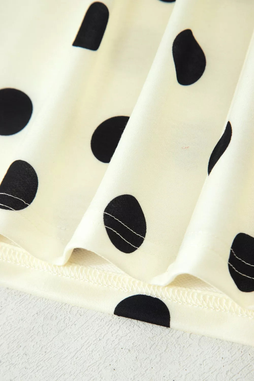 Polka dot print high neck dolman top from Trendsi, featuring a relaxed fit and stylish design, shown in a close-up image.