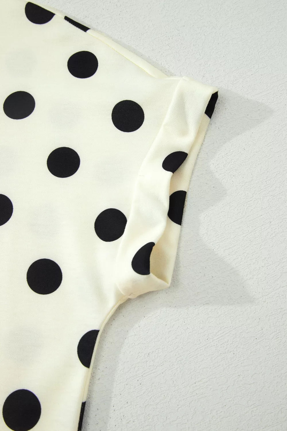 Polka dot print high neck dolman top from Trendsi featuring a relaxed fit and long sleeves, styled on a hanger.