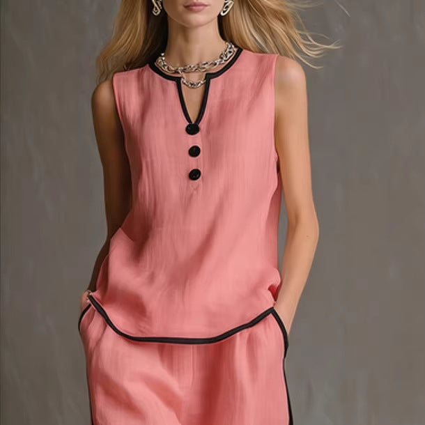 A sleeveless pink top with a black-trimmed V-neck, button placket, and matching pink trousers with black piping.