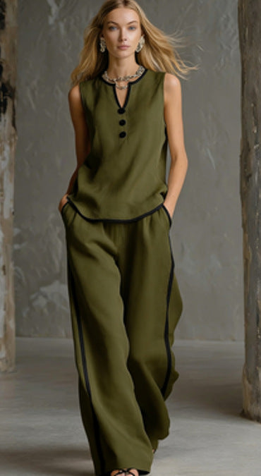 A woman wears a sleeveless olive green top and wide-leg trousers, both detailed with slim black contrast trim.