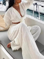 Textured tie-front crop top and wide-leg pants two-piece set by Trendsi, featuring stylish, comfortable fabric in a coordinated outfit.
