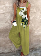 Olive green wide-leg jumpsuit with a large white daisy print, button straps, and side pockets.