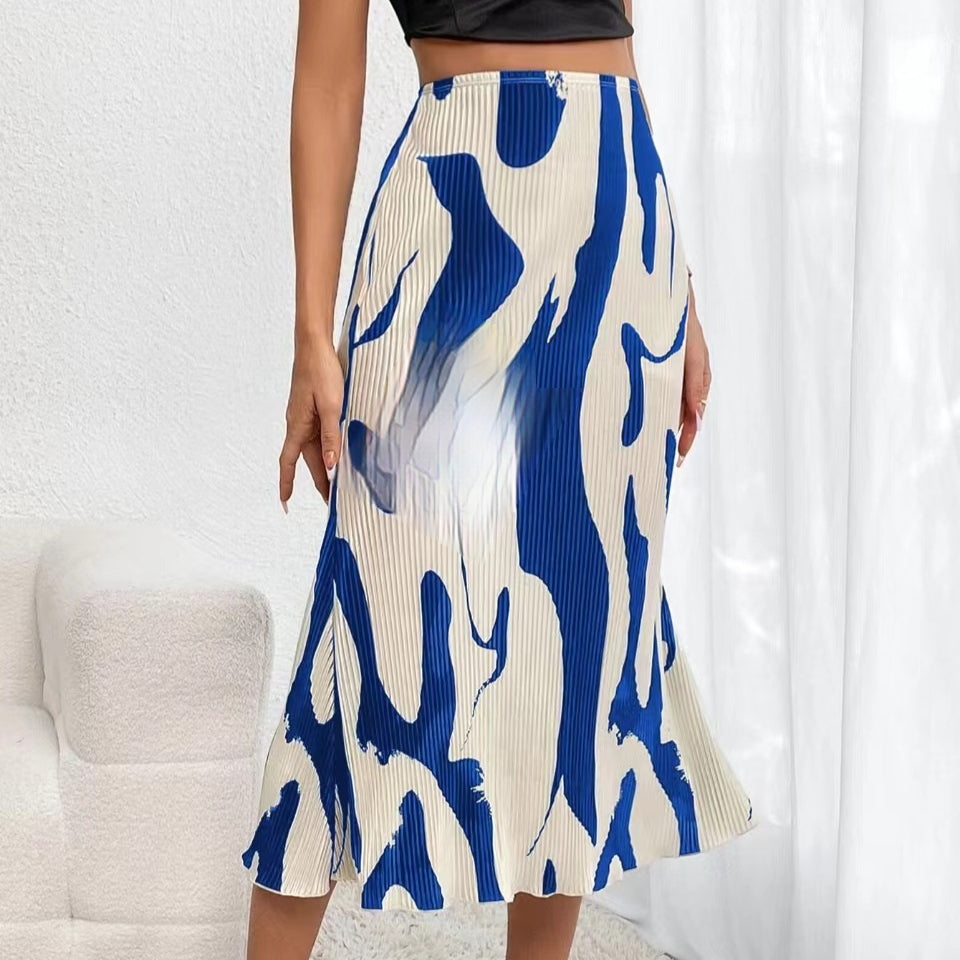 A pleated midi skirt in cream with a bold blue abstract wavy print, worn with a black crop top.