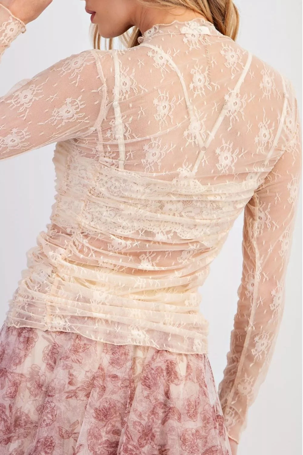 Sheer floral mesh ruched long sleeve top by Trendsi featuring delicate floral patterns and fitted long sleeves.