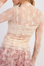Sheer floral mesh ruched long sleeve top by Trendsi featuring delicate floral patterns and fitted long sleeves.