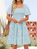 Women's smocked tiered square neck casual dress with short sleeves and pockets, by Trendsi, shown in a stylish, comfortable design.