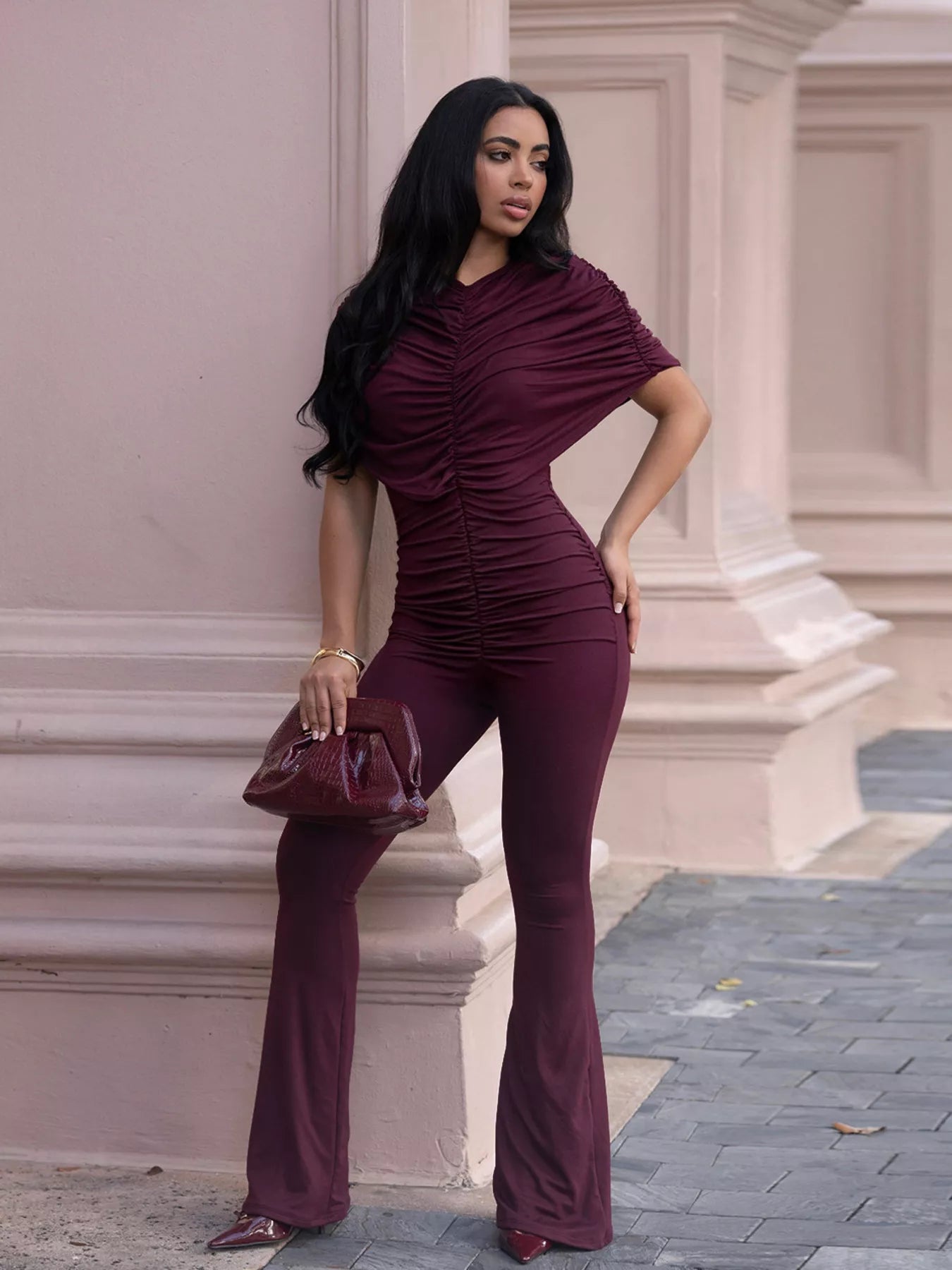 Trendsi ruched flare leg jumpsuit featuring a fitted bodice, adjustable straps, and a flowing wide-leg design on a model.