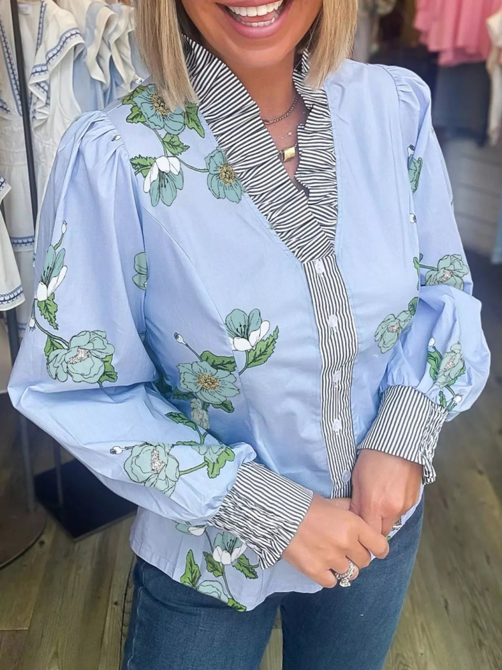 Floral print ruffled V-neck blouse with striped trim, trendy top by Trendsi featuring feminine design and lightweight fabric.
