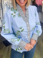 Floral print ruffled V-neck blouse with striped trim, trendy top by Trendsi featuring feminine design and lightweight fabric.