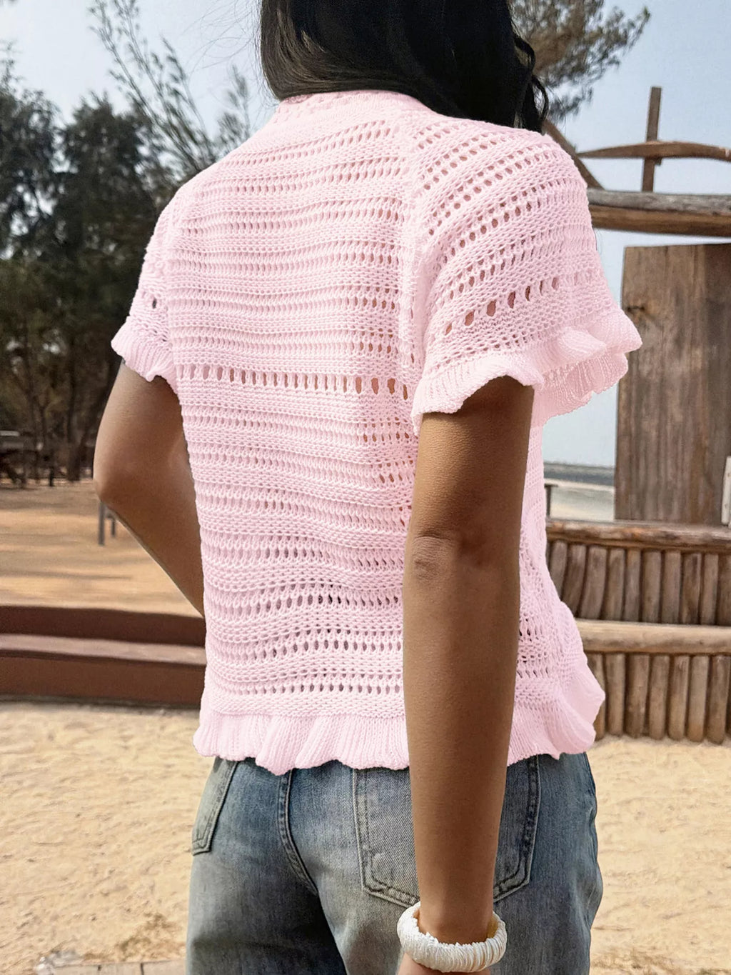 Openwork ruffled hem knit top by Trendsi, featuring a stylish openwork design and feminine ruffled hem for a trendy look.
