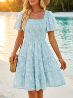 Women's smocked tiered square neck short sleeve casual dress with pockets by Trendsi, featuring a relaxed fit and stylish design.