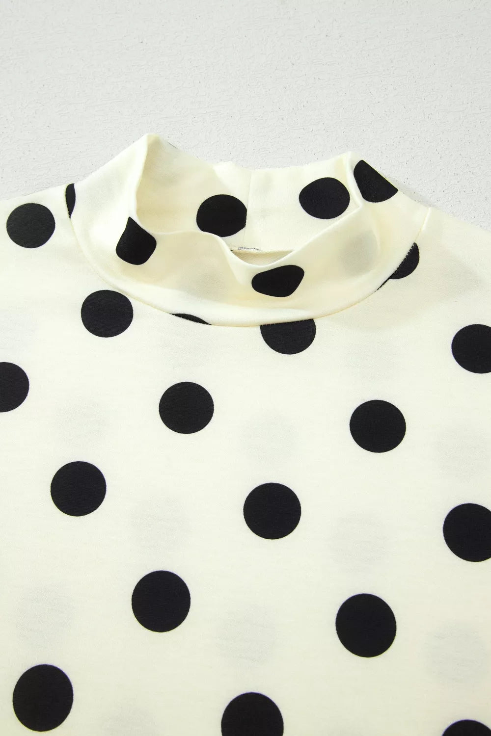 Polka dot print high neck dolman top from Trendsi, featuring a relaxed fit and stylish design in soft fabric.