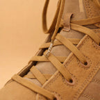 Close-up of a tan suede and canvas lace-up boot with a metallic aglet engraved with the word "BREAD."