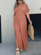 Plus size full-length maxi dress with slit, V-neck, and smocked waist by Trendsi, shown in a stylish, flowing fabric.