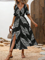 A black and white leaf-print midi dress with cold-shoulder sleeves, a smocked waist, and a side leg slit.