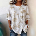 White linen-blend blouse with beige floral embroidery, button front, and decorative side ties.