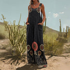Woman wearing a black, wide-leg sleeveless jumpsuit with a sunflower print and side pockets in a desert setting.