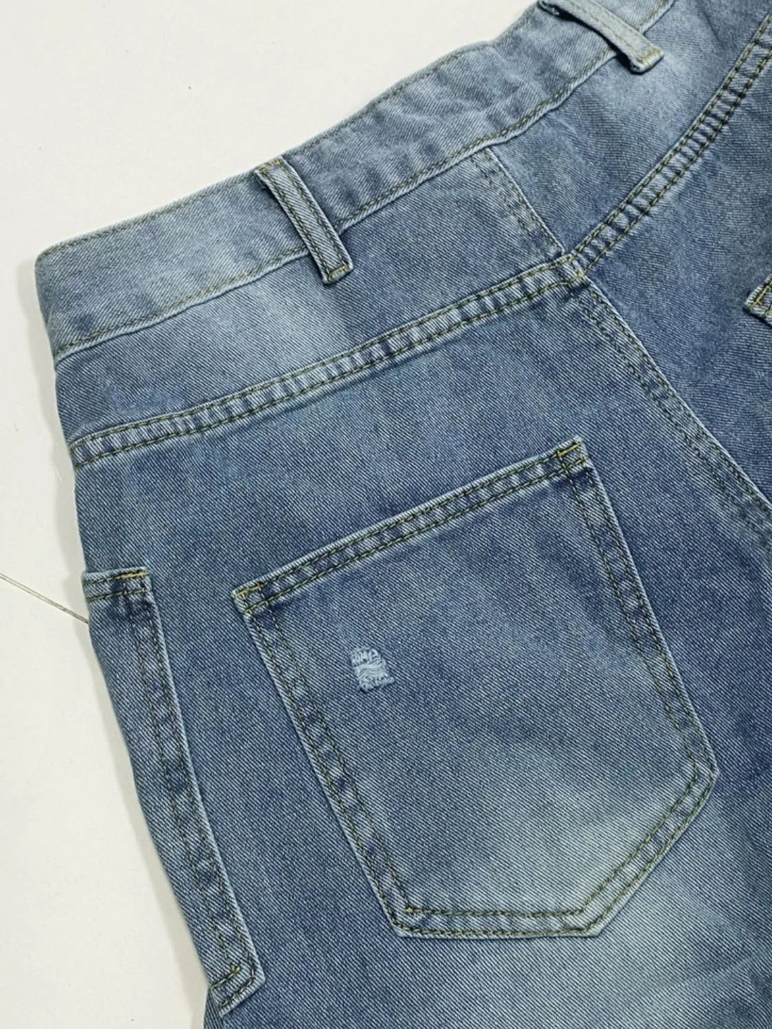 Distressed denim jeans with front and back pockets from Plush Fashion Shop, showcasing a trendy, worn-in look.