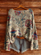 Cream-colored floral knit sweater with blue and red botanical pattern, styled with denim shorts and a leather belt.