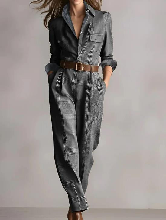 Model wearing a grey plaid jumpsuit with a button-down collar, utility pockets, and a brown leather belt.