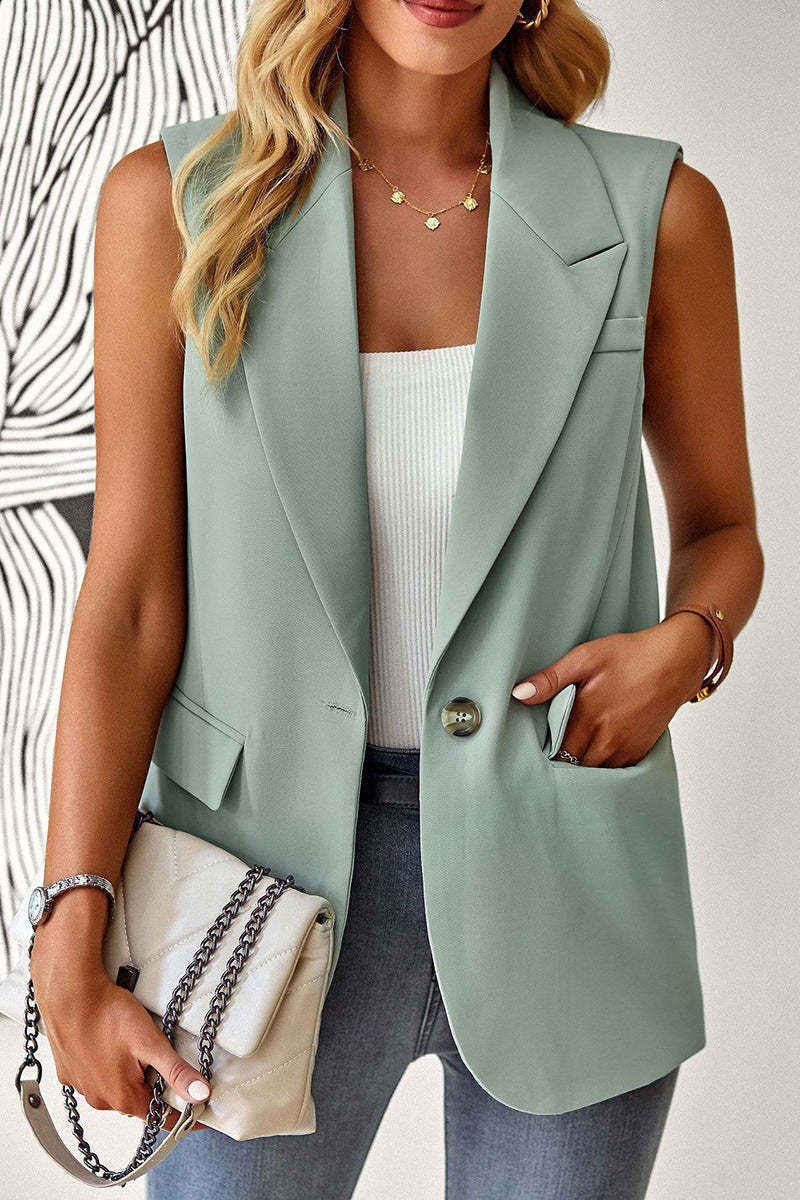 A woman wears a sage green sleeveless blazer vest over a white ribbed top, accessorized with a quilted white bag.