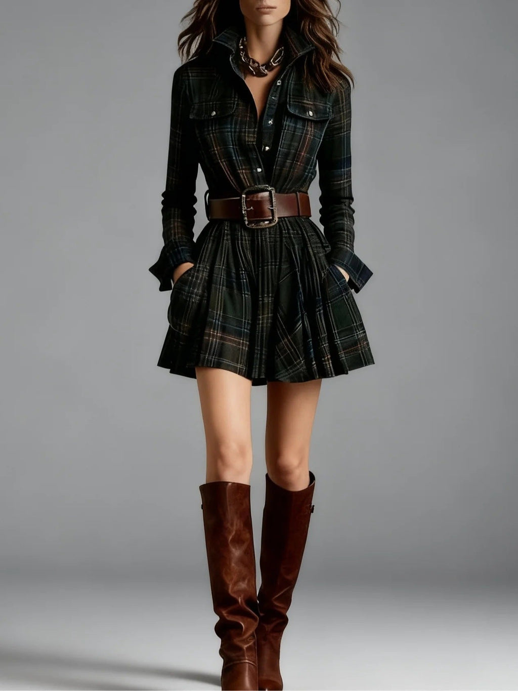 A woman in a dark green plaid shirt dress with a wide brown belt and matching knee-high leather boots.