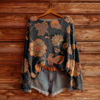 Dark grey loose-fit knit sweater with large orange and gold floral leaf patterns, paired with light wash denim shorts.