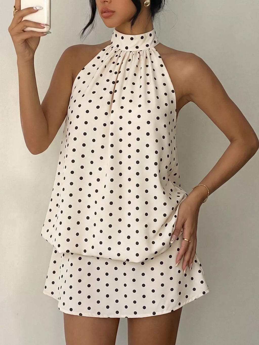 Polka dot halter neck mini dress by Trendsi featuring a fitted silhouette and stylish halter straps.