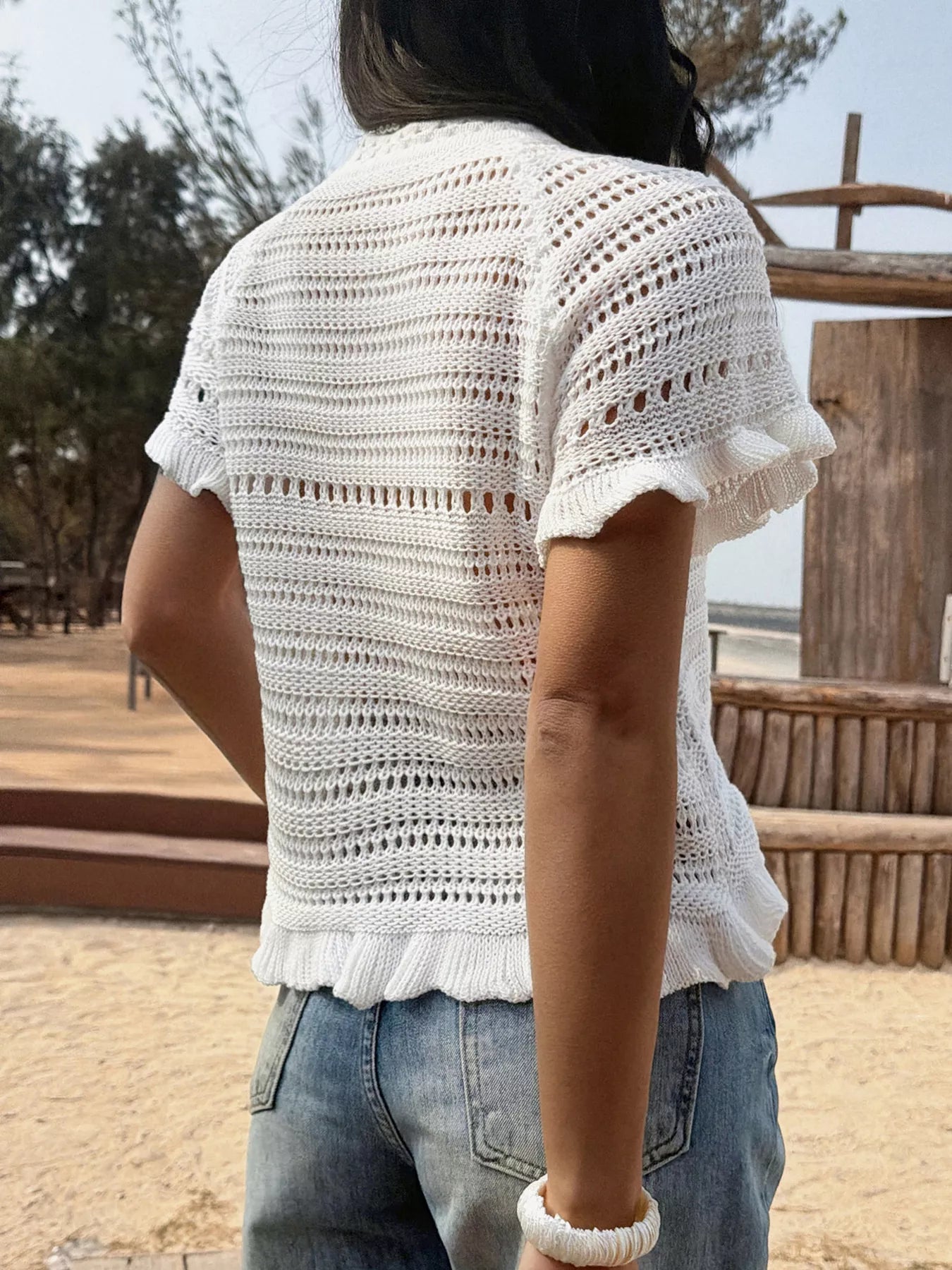 Openwork ruffled hem knit top by Trendsi featuring a textured openwork design and stylish ruffled hem.
