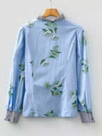 Floral print ruffled V-neck blouse with striped trim, trendy tops by Trendsi, shown with floral and striped design details.