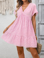 Lightweight plaid V-neck mini dress with ruffle hem from Trendsi, featuring a stylish seasonal design and feminine silhouette.