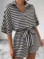Striped button-up belted romper by Trendsi featuring vertical stripes, a collar, and a waist belt for a stylish summer look.