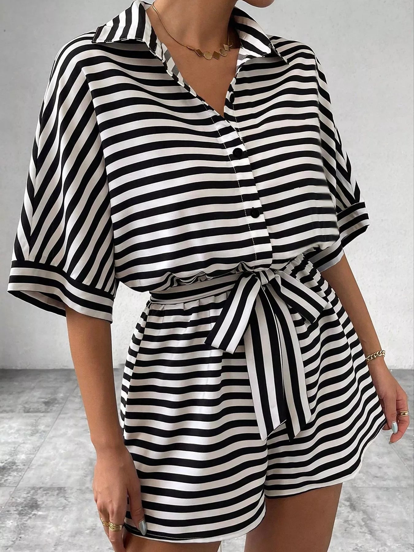 Striped button-up belted romper by Trendsi featuring vertical stripes, a collar, and a waist belt for a stylish summer look.