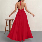 Back view of a red, tiered maxi dress with an open-back, halter neck, and large tie-waist detail.